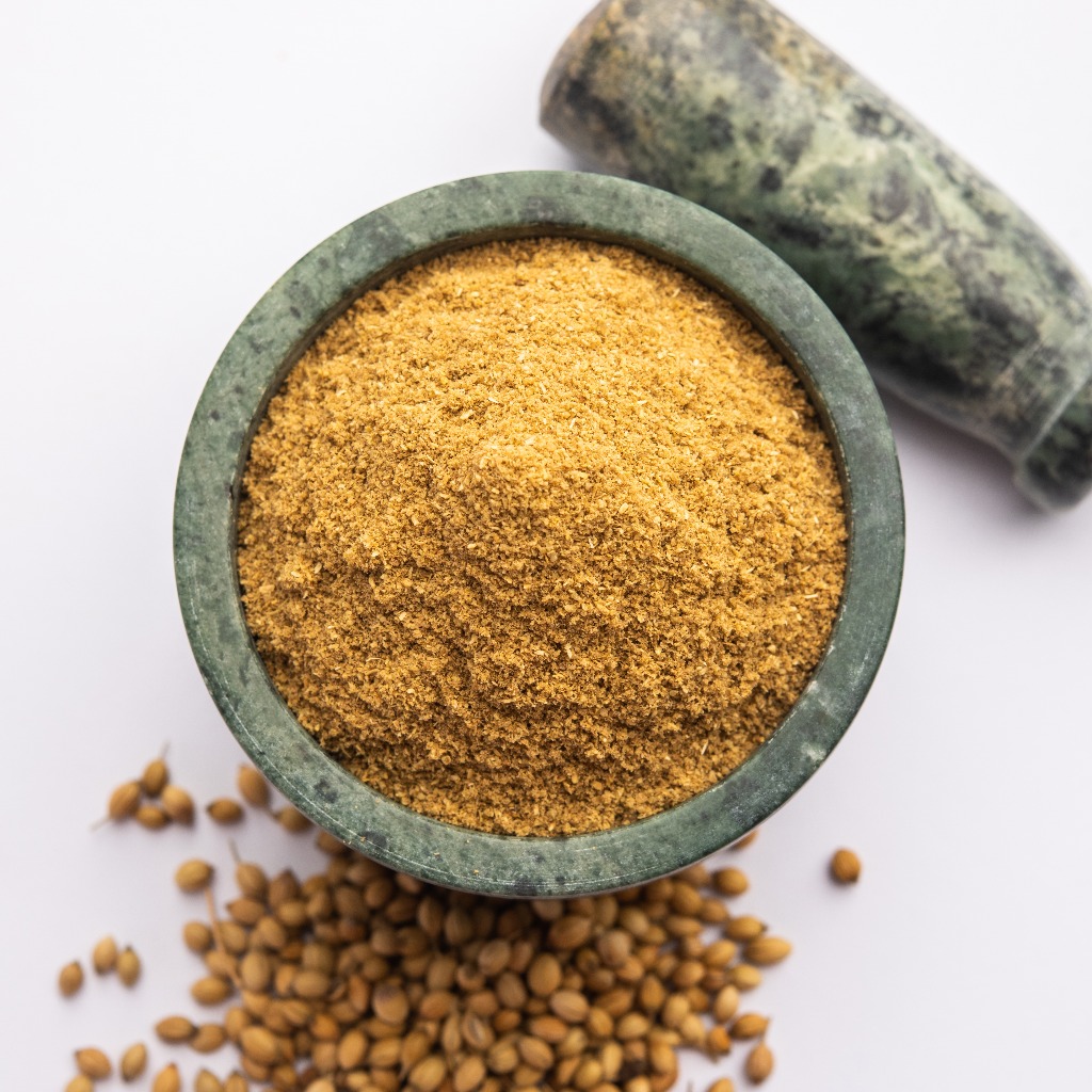 Coriander powder is in a bowl near the Coriander and rock piece.